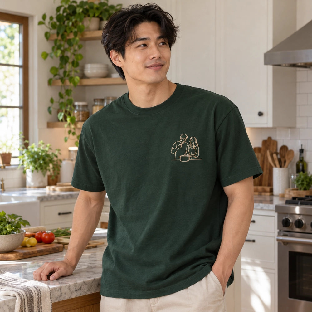 Custom Couple Kitchen Date Outline Embroidered T-Shirt with Back Print - Funny Couple Gift front worn product image with left chest embroidery with custom left chest embroidery based on candid couple cooking together in a bright home kitchen